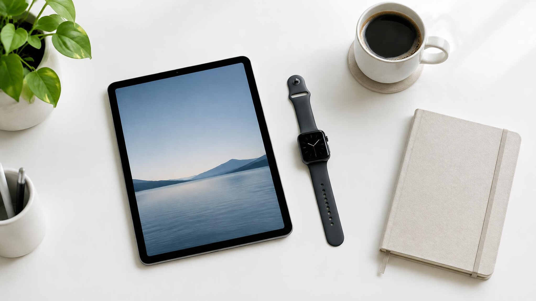 Workspace with tablet, smartwatch and coffee cup on a white desk